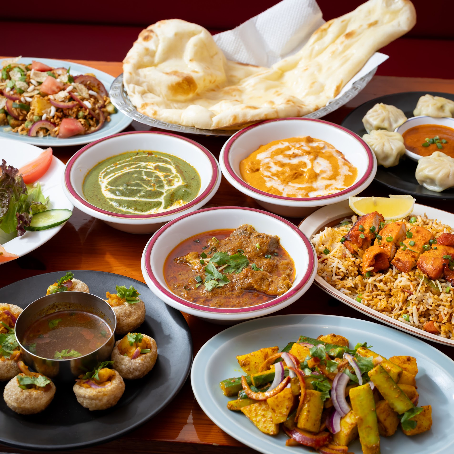 カレー、ナン、モモ、ビリヤニ、パニプリが並ぶマジックキッチンの料理全体写真